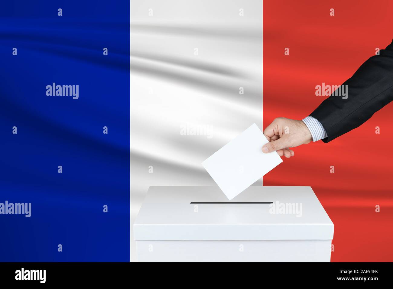 Election in Guadeloupe. The hand of man putting his vote in the ballot box. Waved Guadeloupe flag on background. Stock Photo