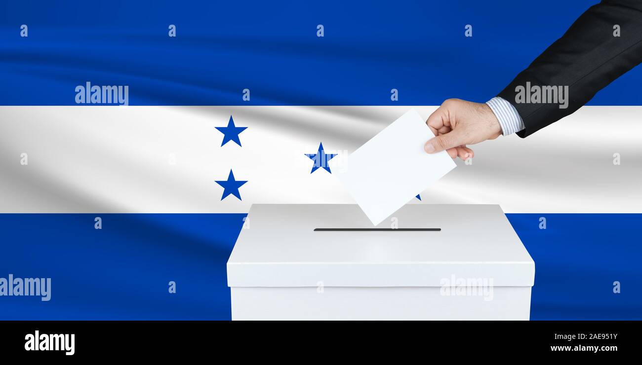 Election in Honduras. The hand of man putting his vote in the ballot box. Waved Honduras flag on background. Stock Photo