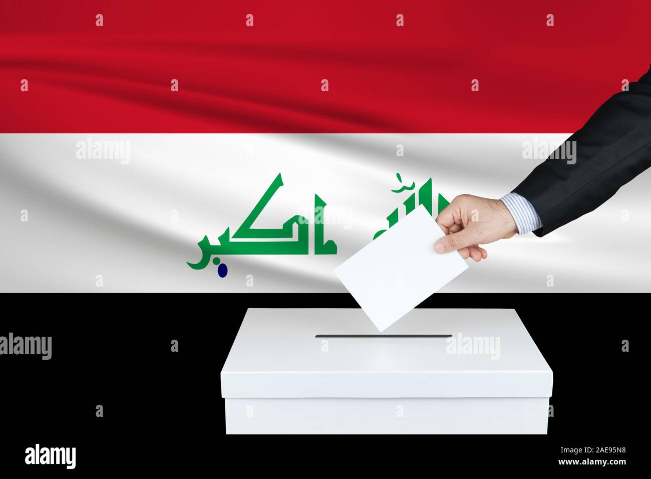Election in Iraq. The hand of man putting his vote in the ballot box. Waved Iraq flag on background. Stock Photo