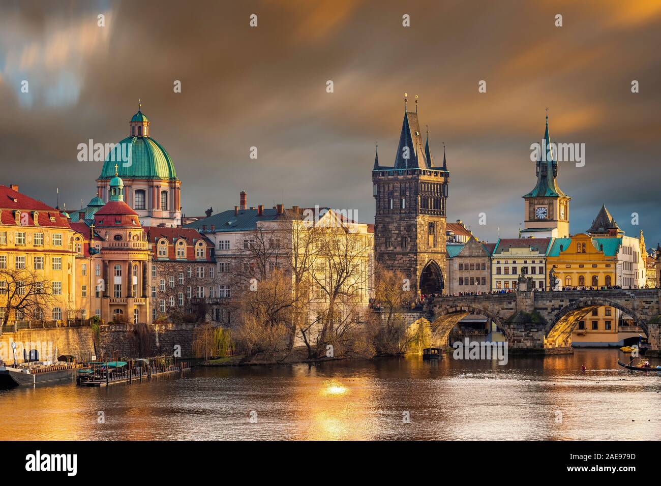 Prague, Czech Republic - The world famous Charles Bridge (Karluv most) with St. Francis of Assisi Church and clocktower with beautiful golden sunset l Stock Photo