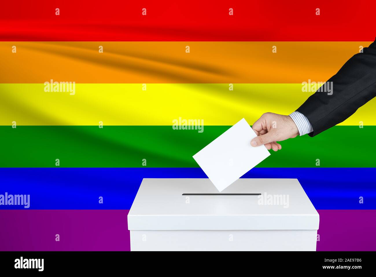 Election in Lgbt. The hand of man putting his vote in the ballot box. Waved Trans flag on background. Stock Photo