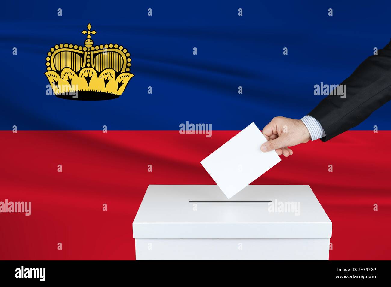 Election in Liechtenstein. The hand of man putting his vote in the ballot box. Waved Liechtenstein flag on background. Stock Photo