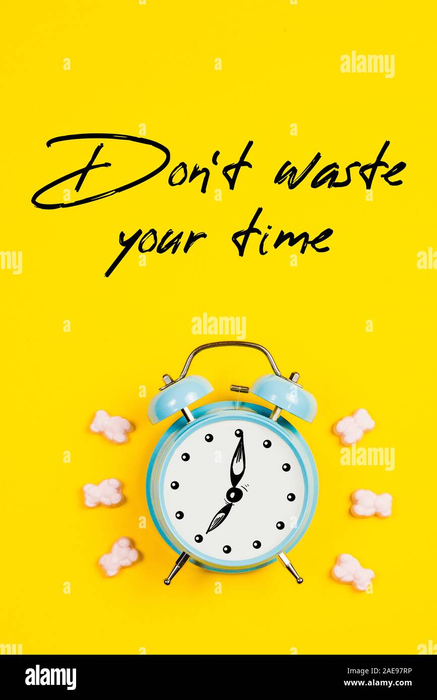 Blue alarm clock with graphics and text Don't waste your time on yellow background Stock Photo