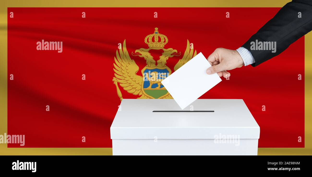 Election in Montenegro. The hand of man putting his vote in the ballot box. Waved Montenegro flag on background. Stock Photo