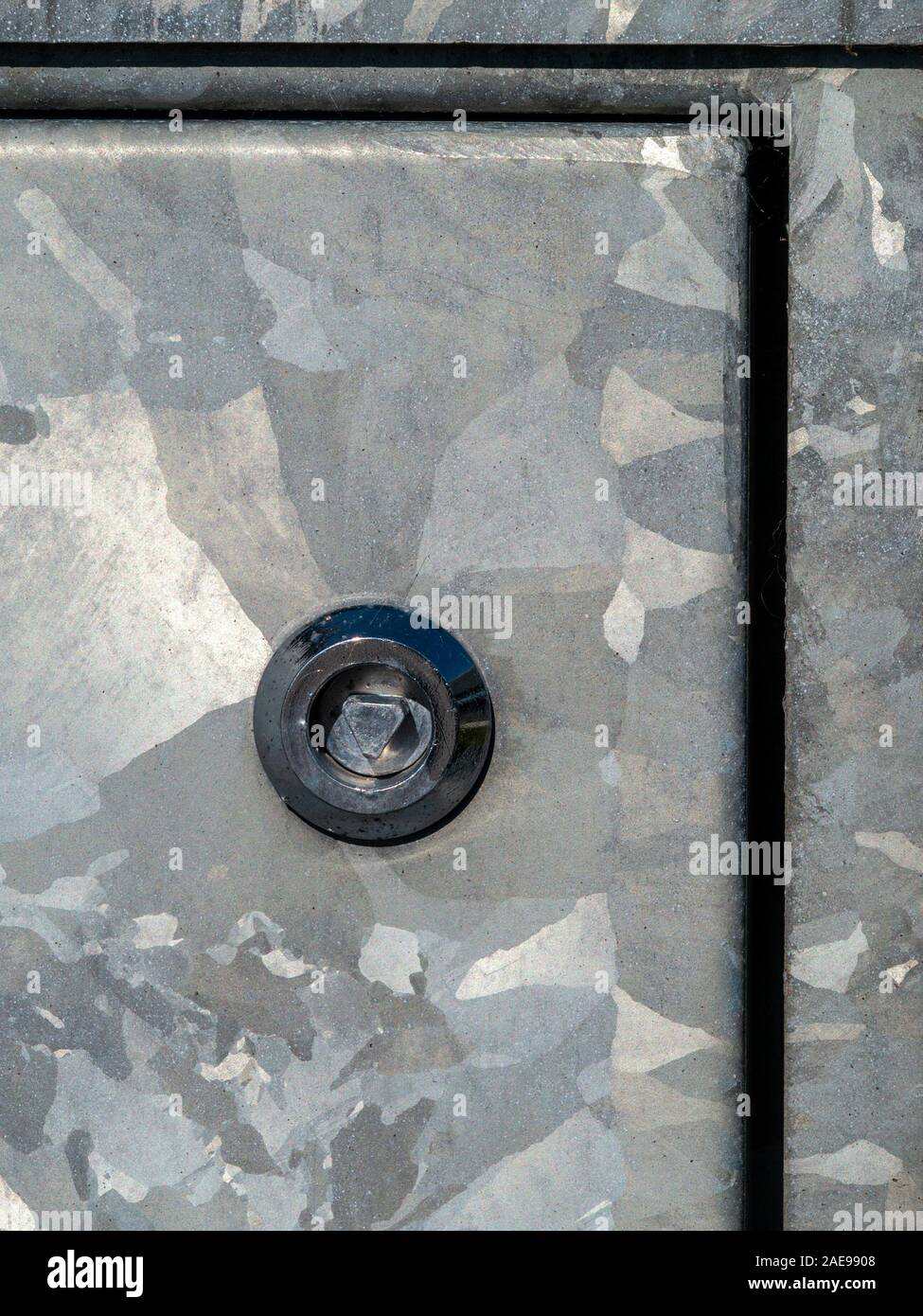 Closeup of zinc galvanised surface of service cabinet showing triangle key lock and zinc grain structure / spangle, Isle of Colonsay, Scotland, UK Stock Photo