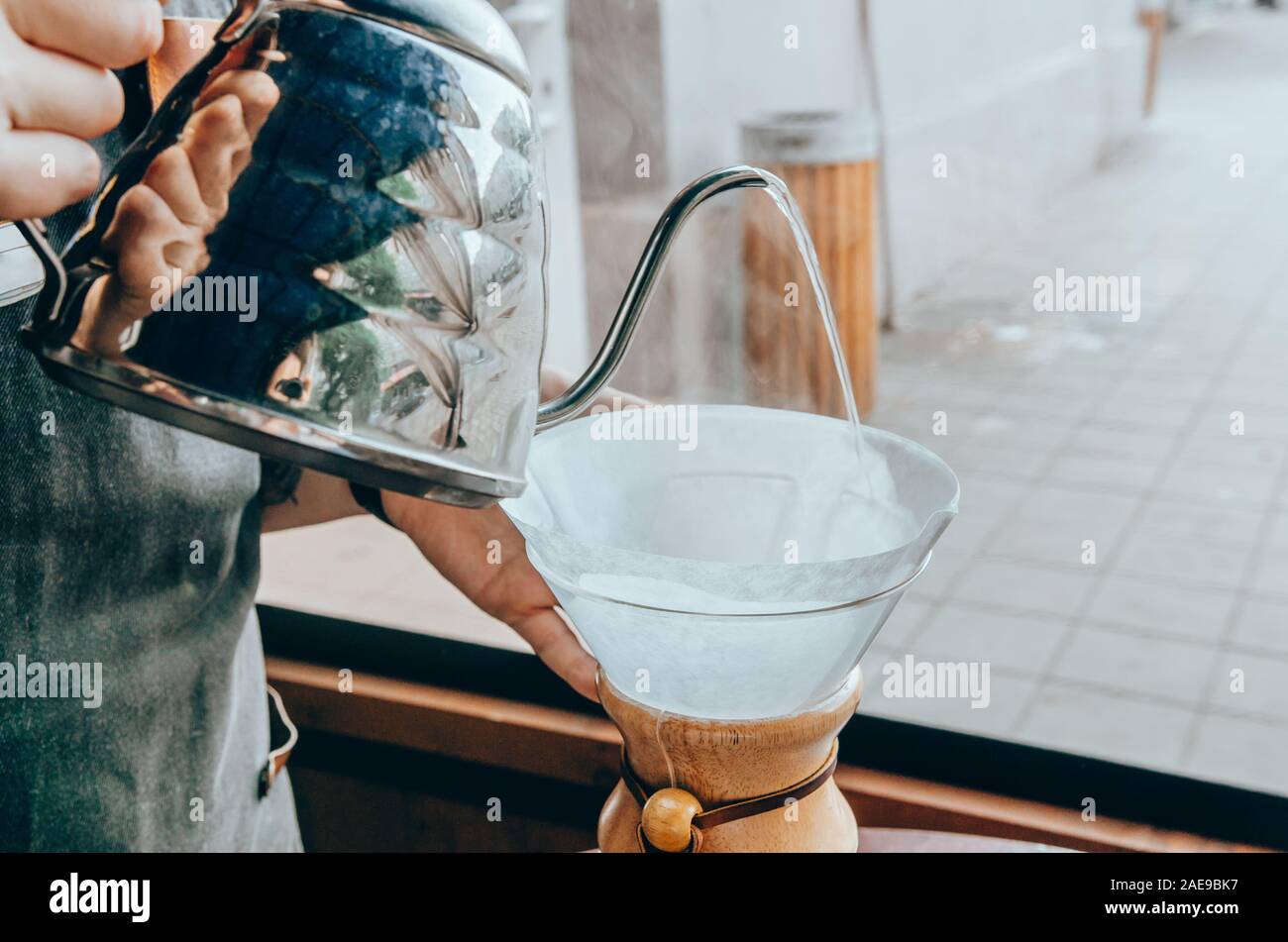 Barista preparing filter coffee outdoor. Young male barista pouring