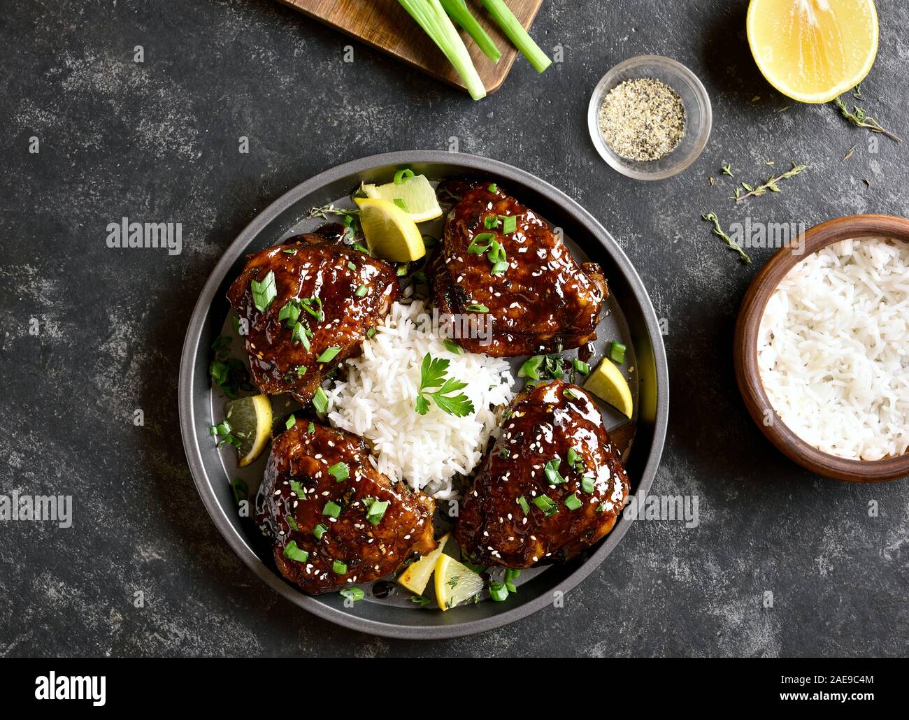 Honey soy sauce grilled chicken thighs with rice over dark stone