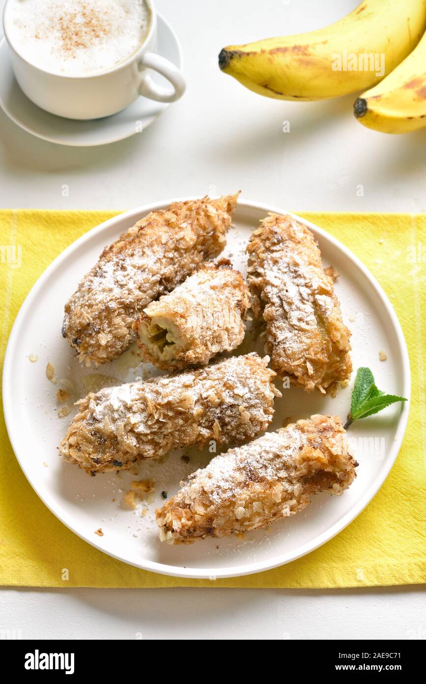 Deep fried bananas on plate over white stone background. Tasty dessert