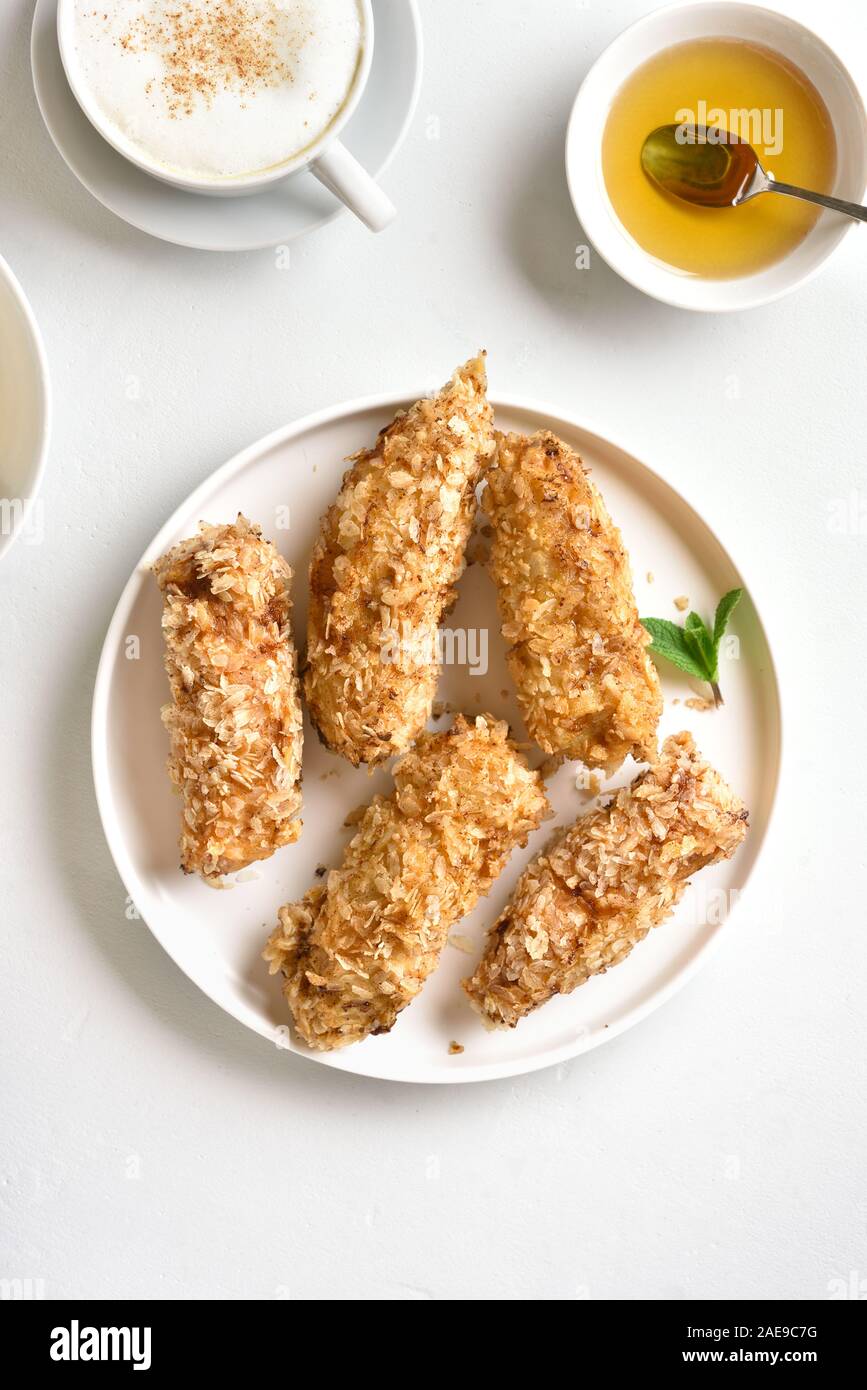Deep fried bananas on plate over white stone background. Tasty dessert