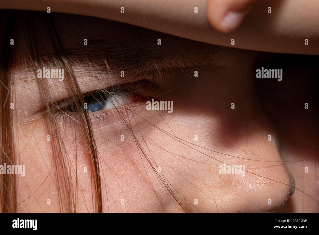 Close up of a baby girl's face. A child covering his eyes from the glaring rays of the sun. Stock Photo
