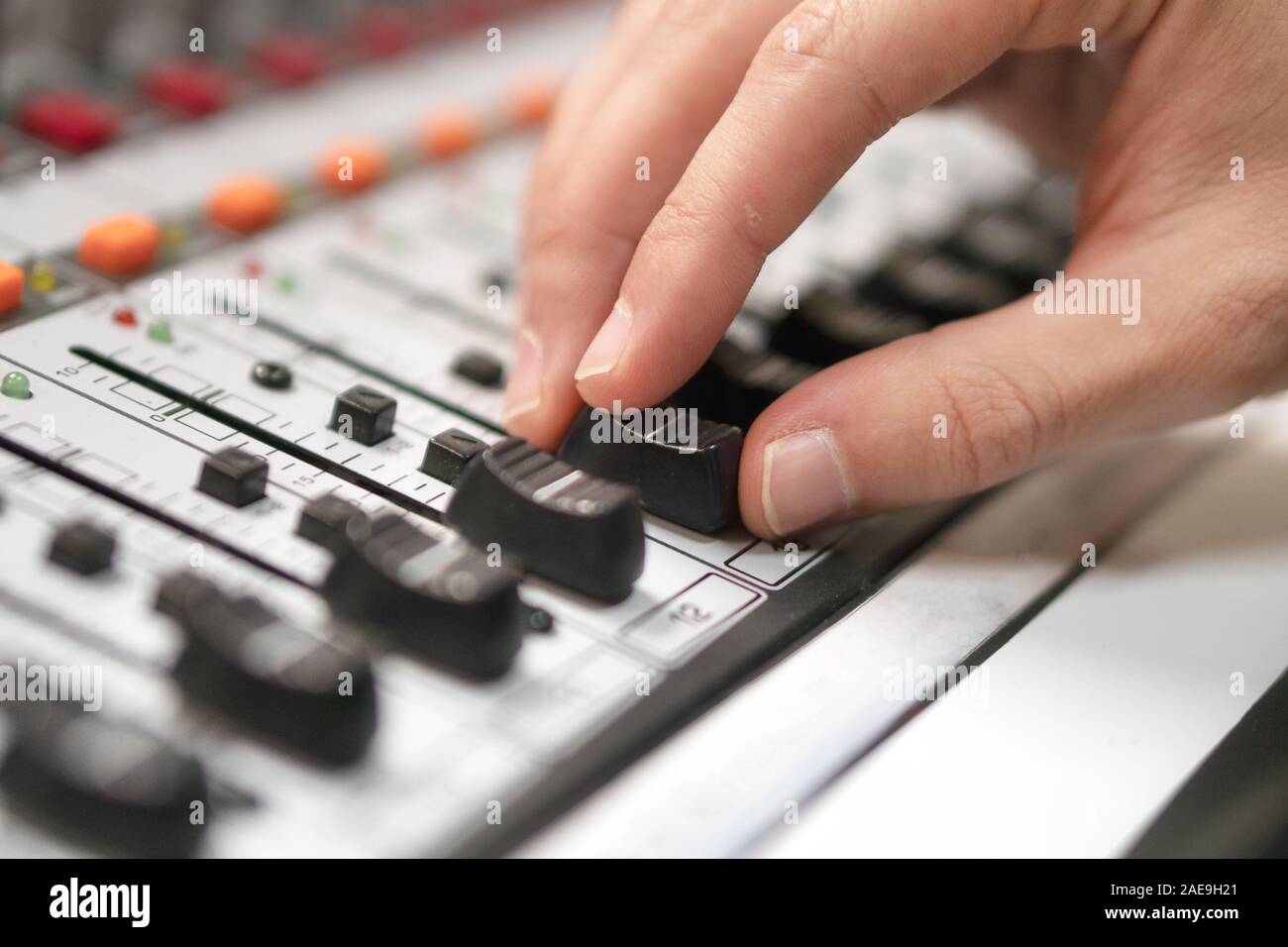 Male hand on control Fader on console. Sound recording studio mixing desk with engineer or music producer . Stock Photo