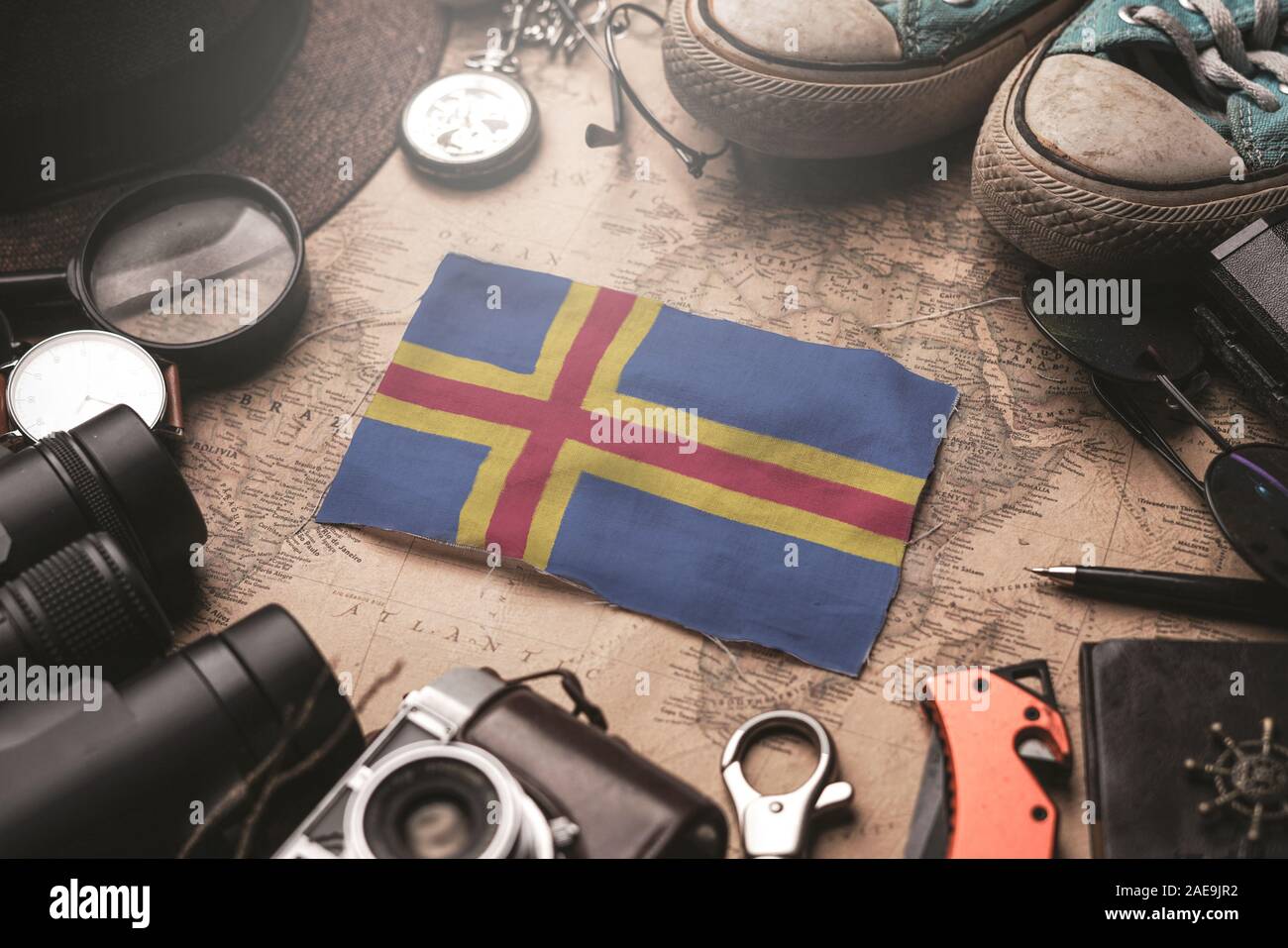 Aland Islands Flag Between Traveler's Accessories on Old Vintage Map. Tourist Destination Concept. Stock Photo