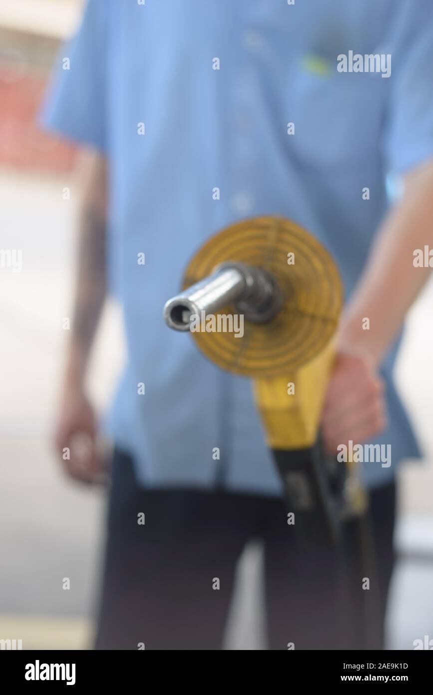 Young male holding a fuel hose at a gas station Stock Photo