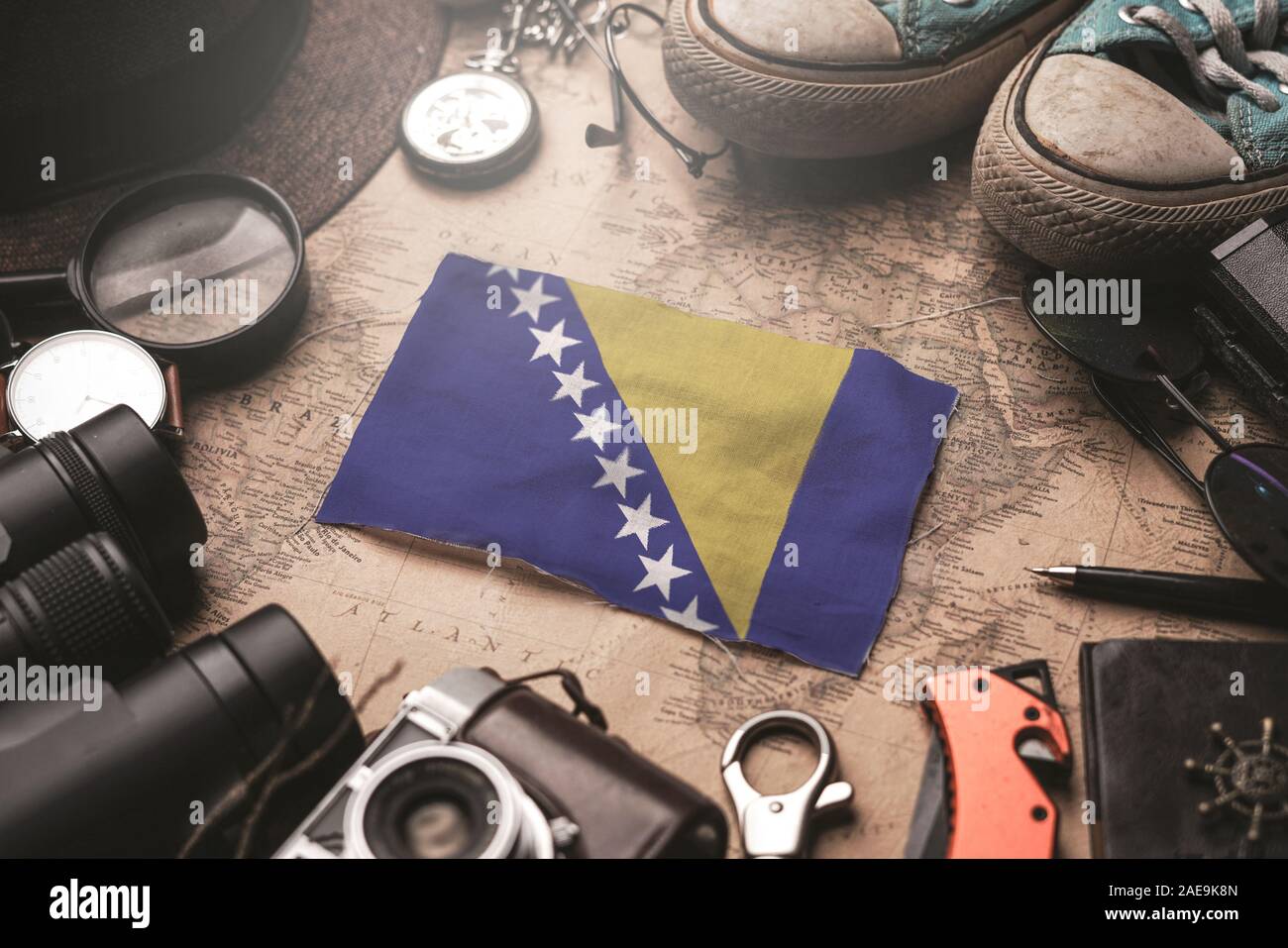 Bosnia and Herzegovina Flag Between Traveler's Accessories on Old Vintage Map. Tourist Destination Concept. Stock Photo