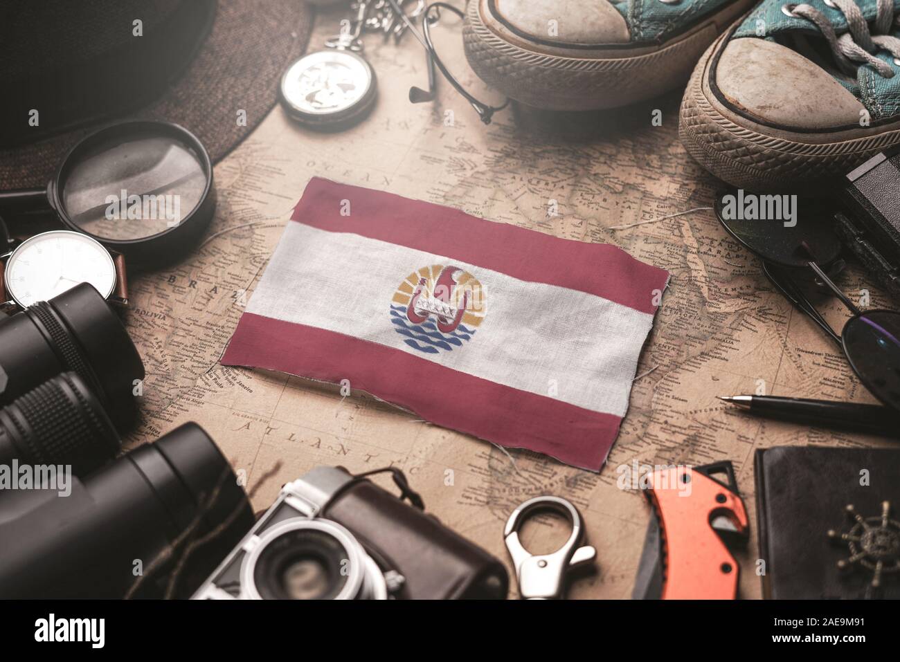 French Polynesia Flag Between Traveler's Accessories on Old Vintage Map. Tourist Destination Concept. Stock Photo