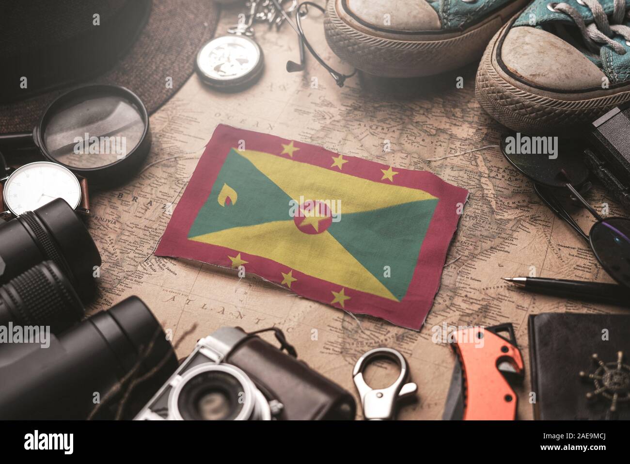 Grenada Flag Between Traveler's Accessories on Old Vintage Map. Tourist Destination Concept. Stock Photo