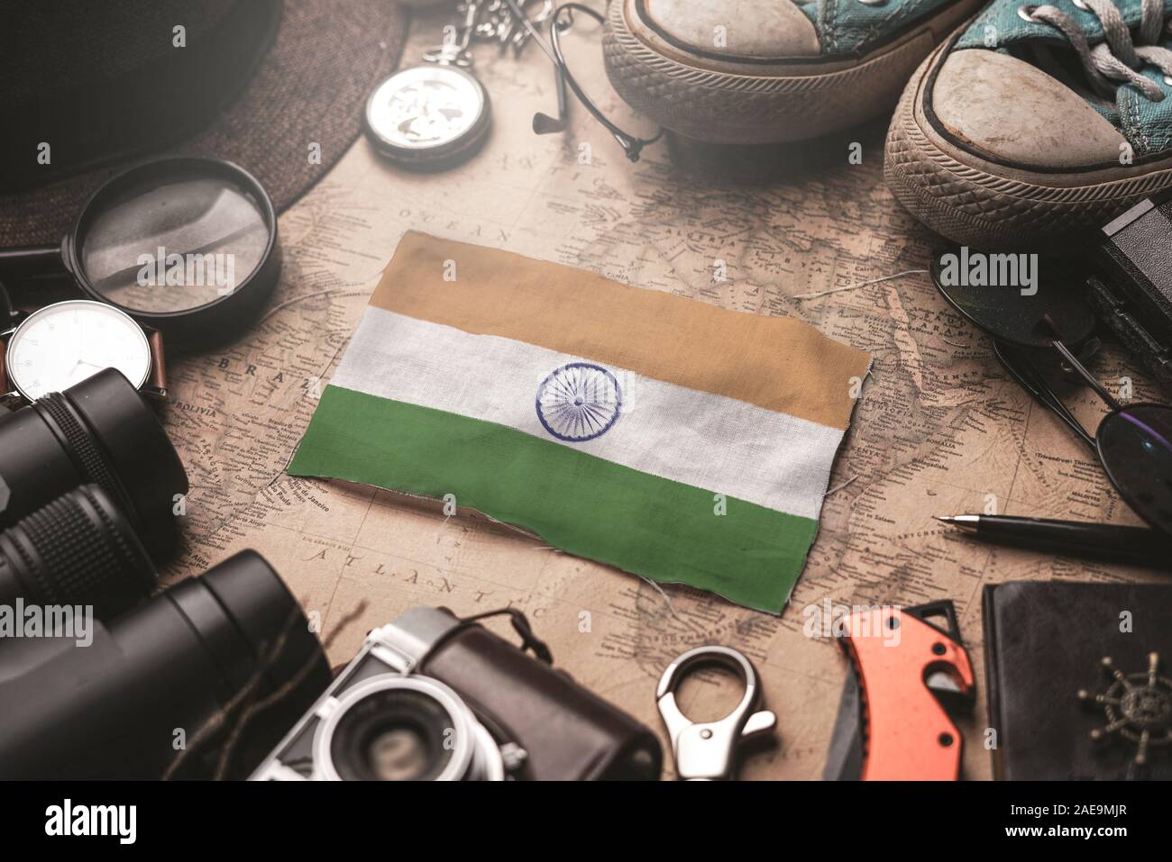India Flag Between Traveler's Accessories on Old Vintage Map. Tourist Destination Concept. Stock Photo