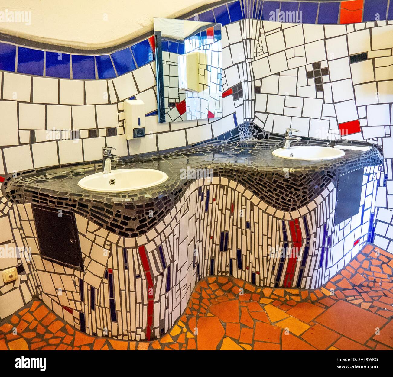 Wash basins and quirky wall tiling toilets of Bahnhof Uelzen railway station renovated by architect Friedensreich Hundertwasser Lower Saxony Germany. Stock Photo