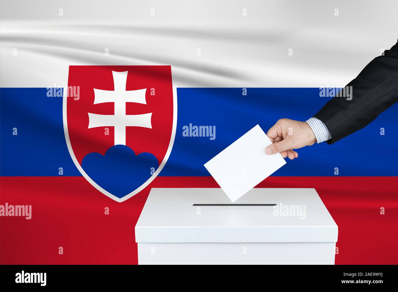 Election in Slovakia. The hand of man putting his vote in the ballot box. Waved Slovakia flag on background. Stock Photo