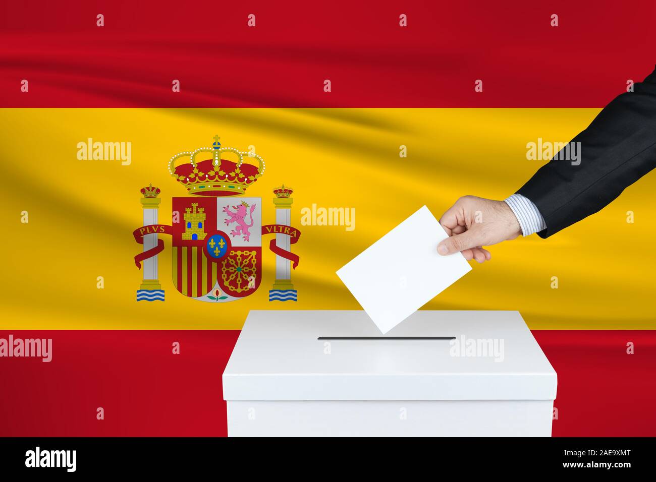 Election in Spain. The hand of man putting his vote in the ballot box. Waved Spain flag on background. Stock Photo