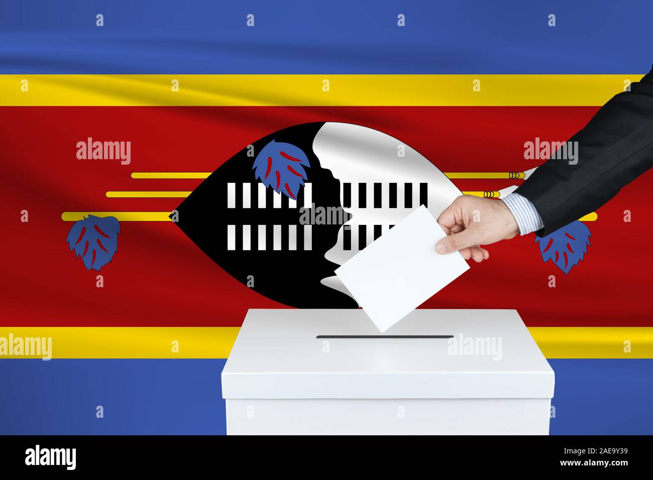 Election in Swaziland. The hand of man putting his vote in the ballot box. Waved Swaziland flag on background. Stock Photo