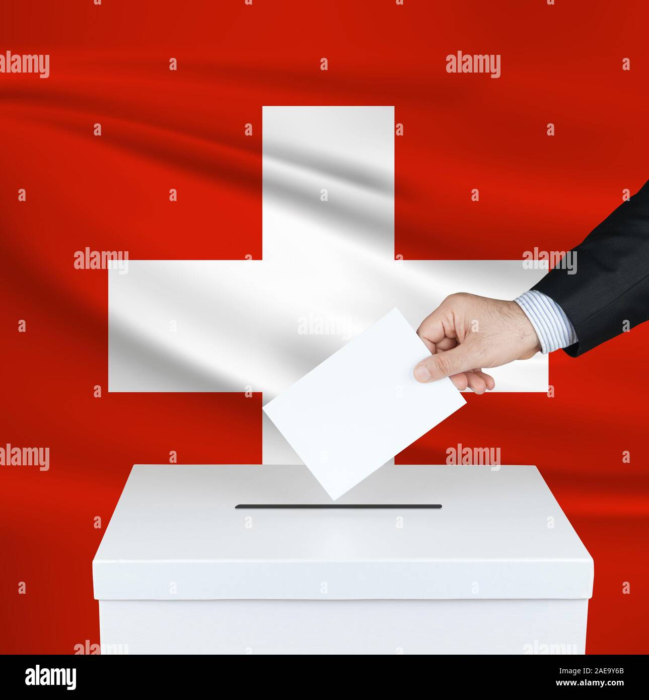 Election in Switzerland. The hand of man putting his vote in the ballot box. Waved Switzerland flag on background. Stock Photo