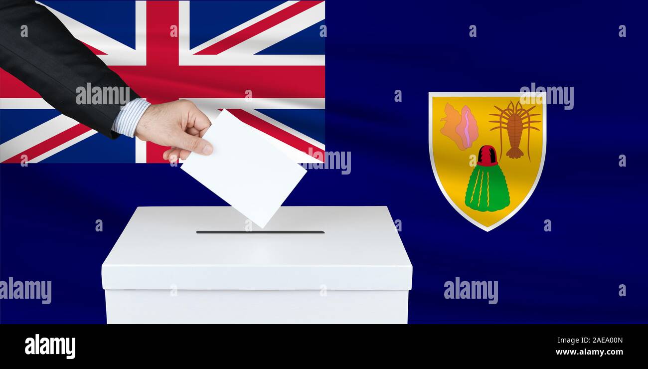 Election in Turks Caicos. The hand of man putting his vote in the ballot box. Waved Turks Caicos flag on background. Stock Photo