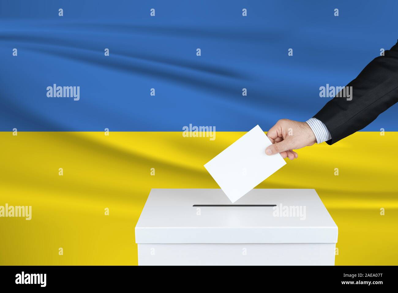 Election in Ukraine. The hand of man putting his vote in the ballot box. Waved Ukraine flag on background. Stock Photo