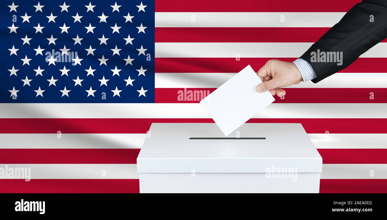 Election in United States. The hand of man putting his vote in the ballot box. Waved United States flag on background. Stock Photo