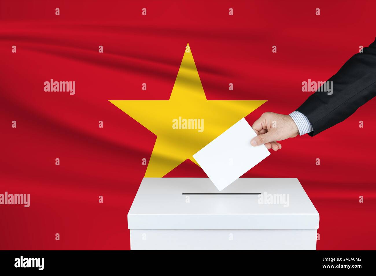 Election in Turkey. The hand of man putting his vote in the ballot box. Waved Turkish flag on background. Stock Photo
