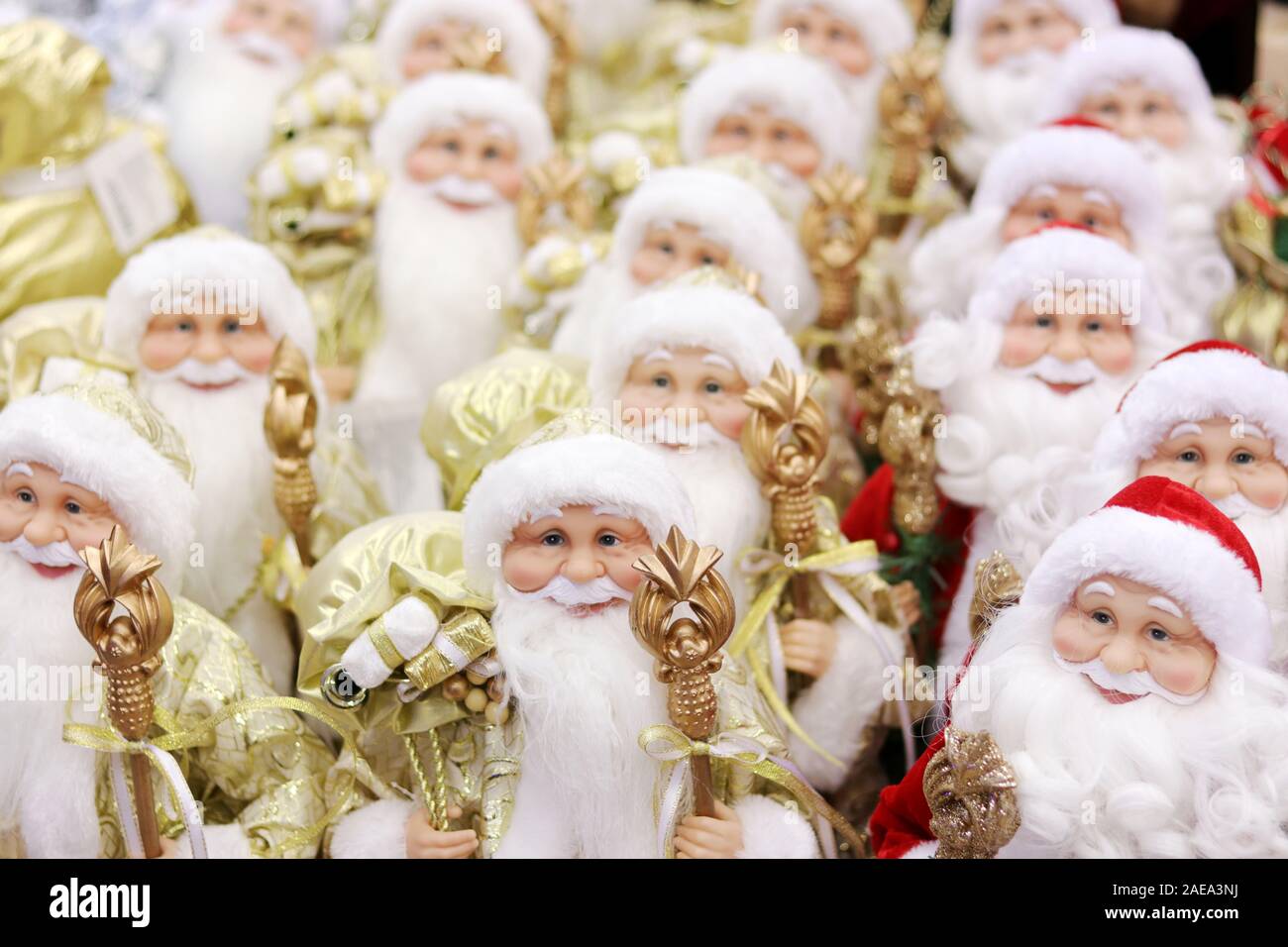 Christmas background filled with many Santa Claus dolls figures in red and gold suits stand in rows for winter holidays. Stock Photo