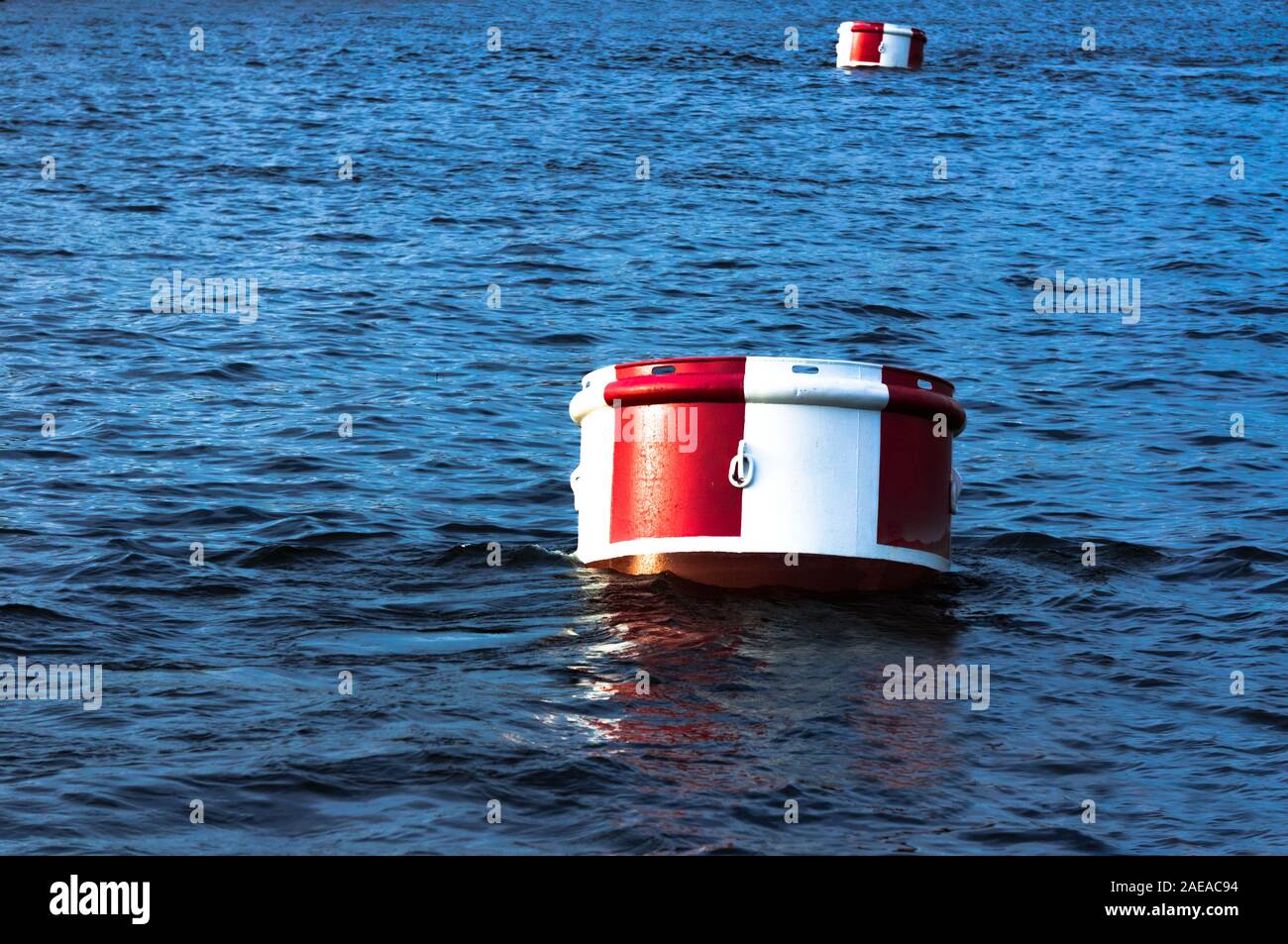 Big round red and white buoy on surface of blue water Stock Photo