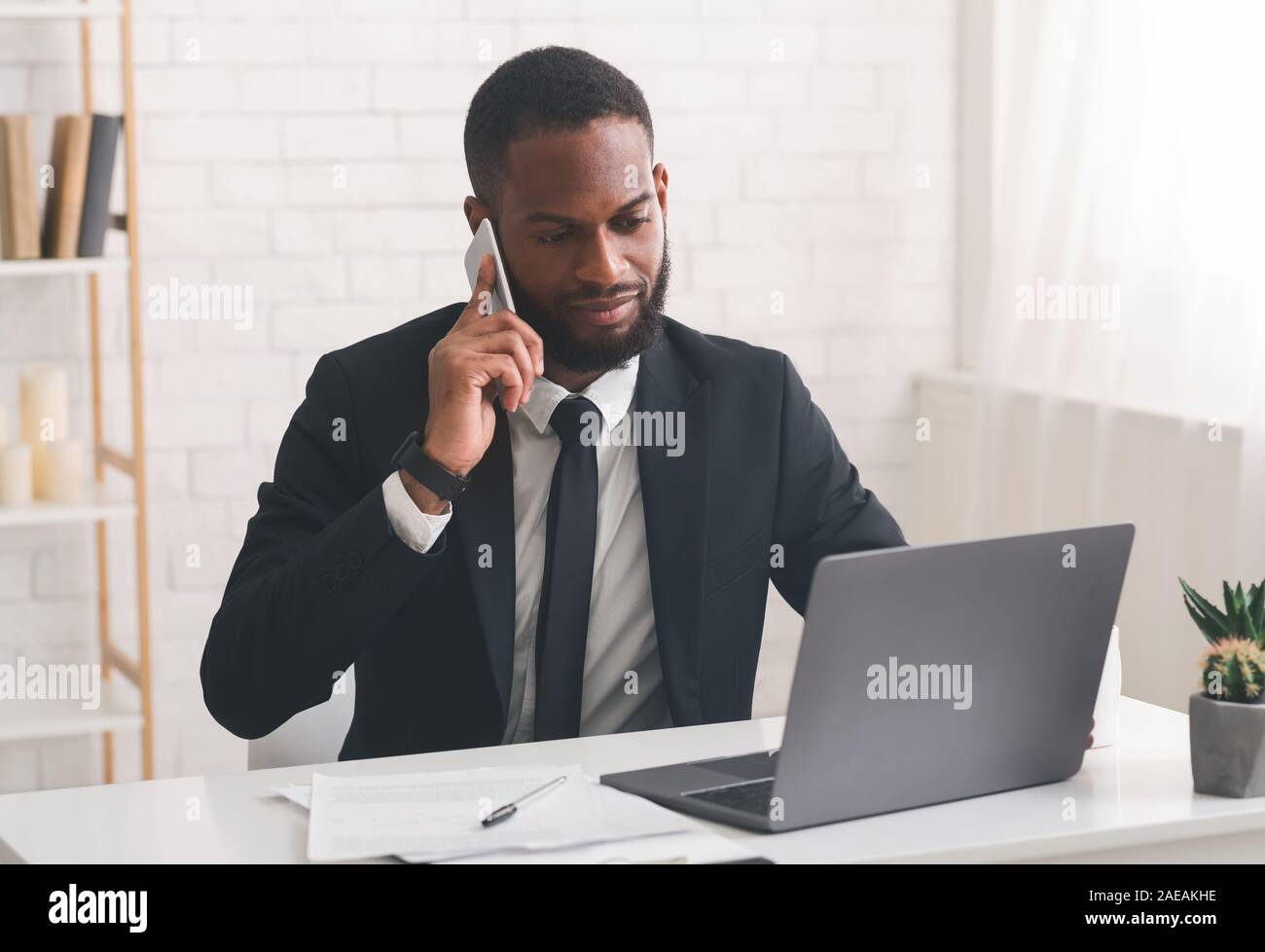 Serious entrepreneur having phone conversation, using laptop Stock Photo