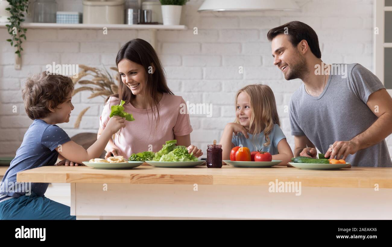 Couple with children sitting at kitchen countertop preparing healthy dinner Stock Photo