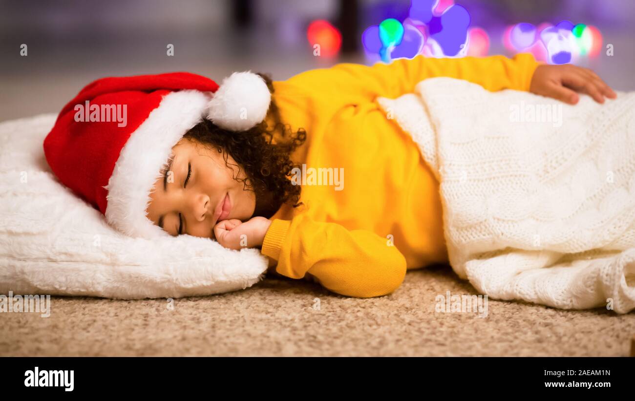 Adorable african little girl sleeping on floor on Christmas night Stock