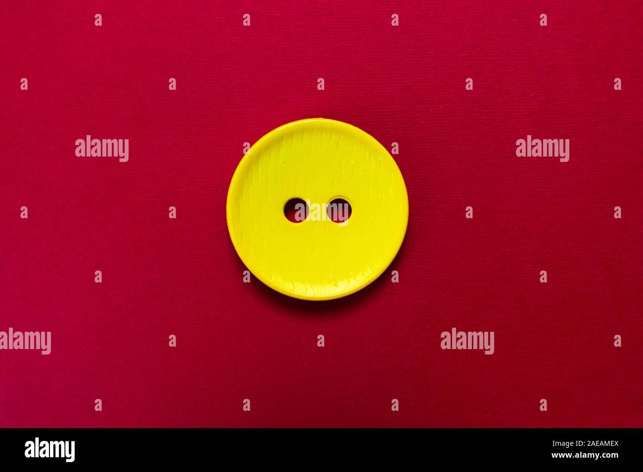 Big yellow button isolated on red background. Stock Photo