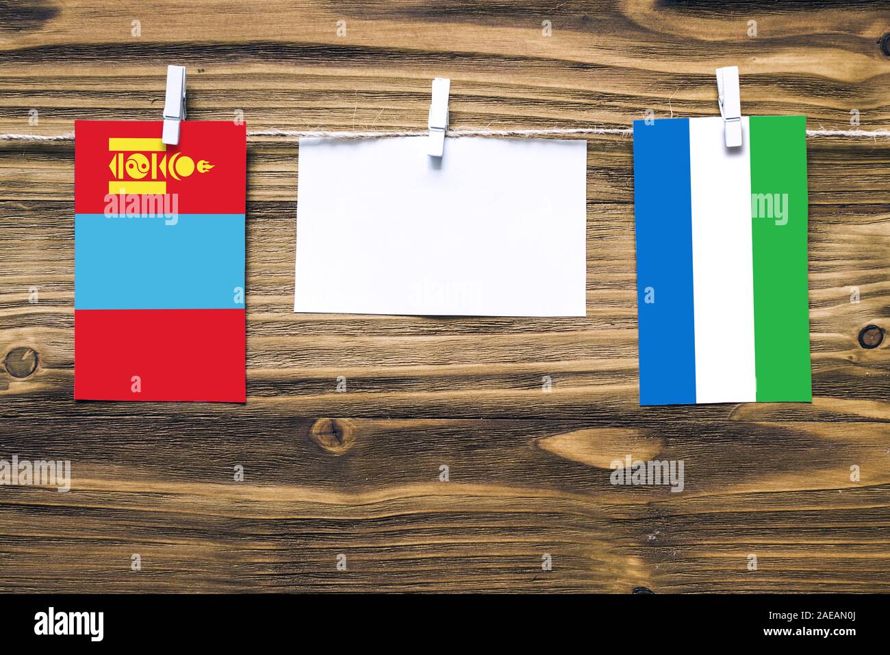 Hanging flags of Mongolia and Sierra Leone attached to rope with clothes pins with copy space on white note paper on wooden background.Diplomatic rela Stock Photo