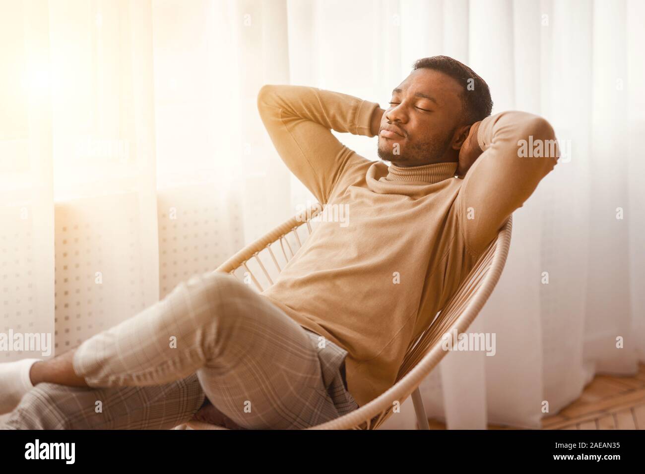 Peaceful Black Man Sitting On Modern Chair At Home Stock Photo