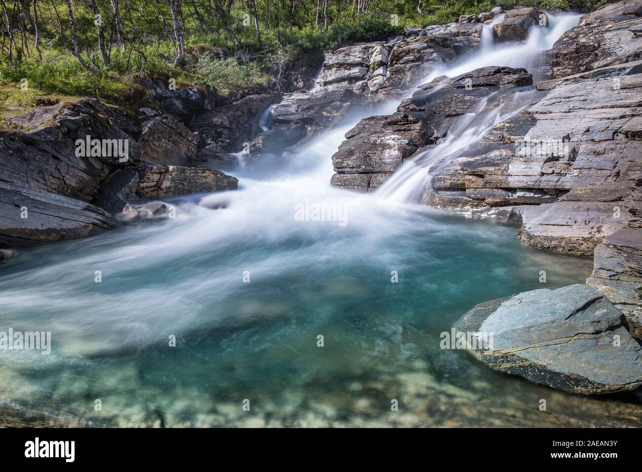 Waterfall landscape with flowing river and rock at sunny summer day in Abisko, Sweden. Silverfallet. Stock Photo