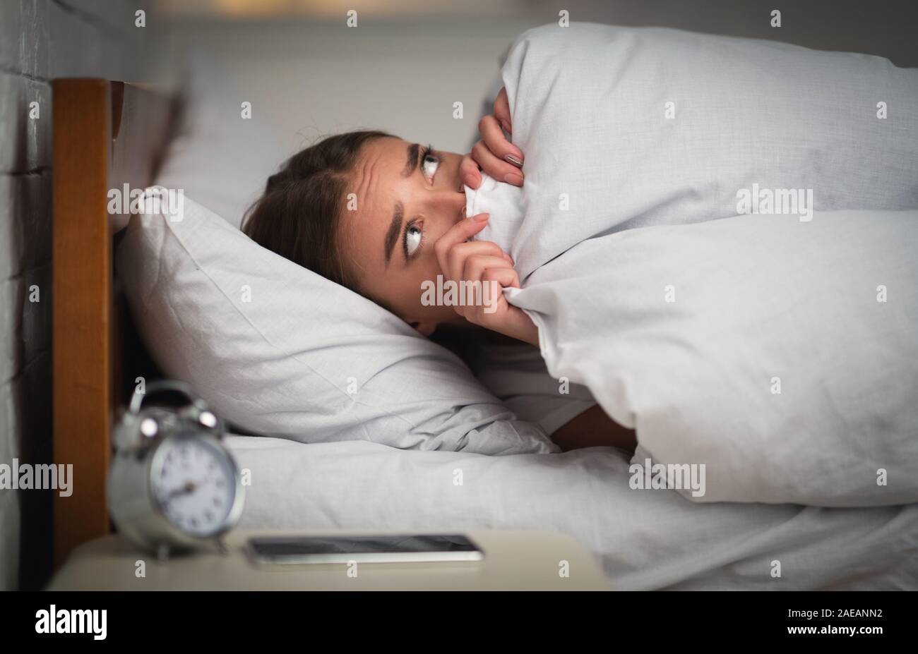 Scared Girl Lying In Bed Unable To Get To Sleep Stock Photo