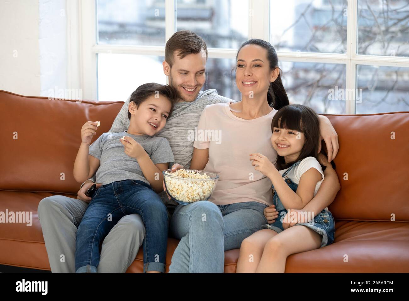 Happy young family and preschool children watching funny tv show Stock