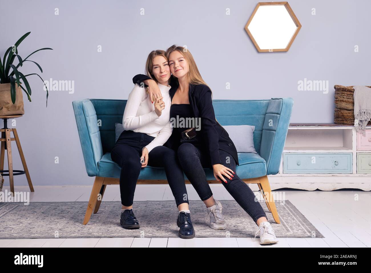 Two girls embrace each other. They are sitting on the couch at home. They  are in a good mood. They are happy with each other Stock Photo - Alamy