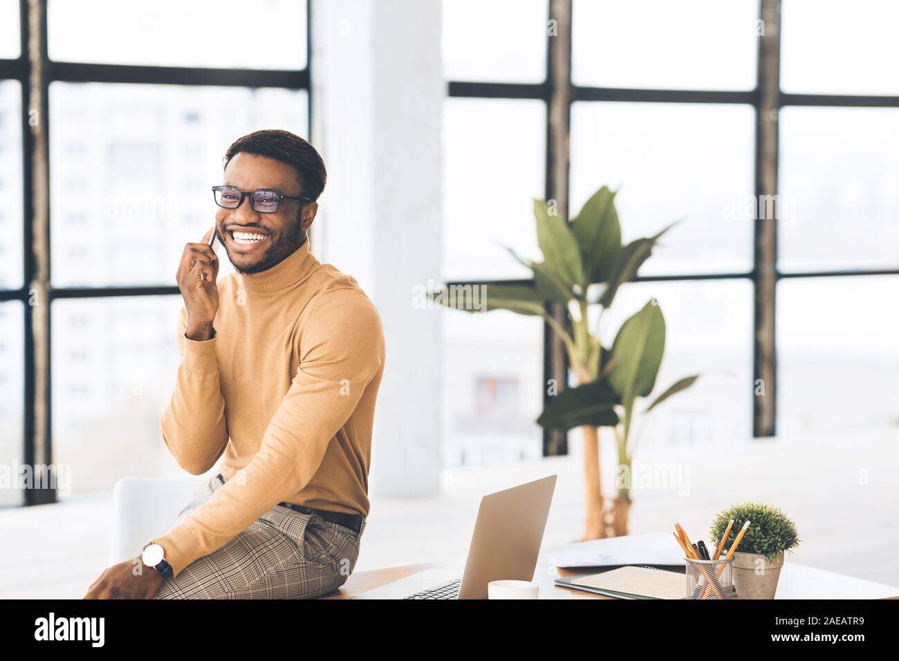 Black guy talking on phone sitting on the table Stock Photo