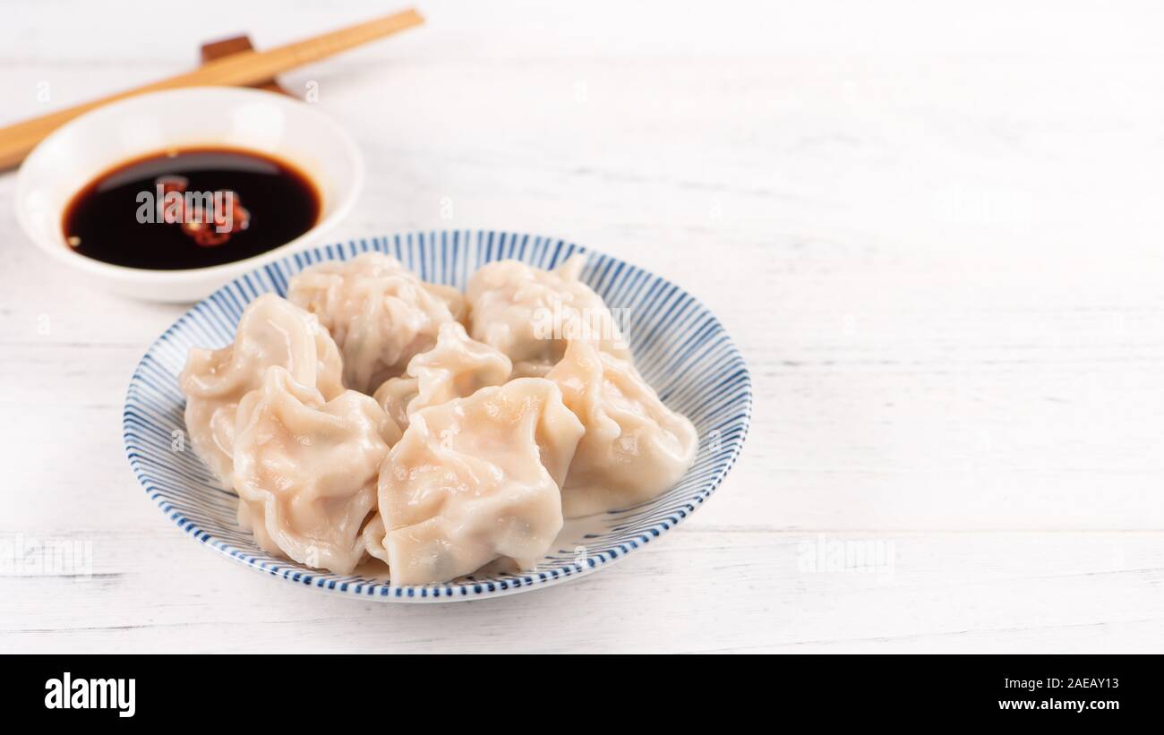 Fresh, delicious boiled pork gyoza dumplings, jiaozi on white background with soy sauce and chopsticks, close up, lifestyle. Homemade design concept. Stock Photo