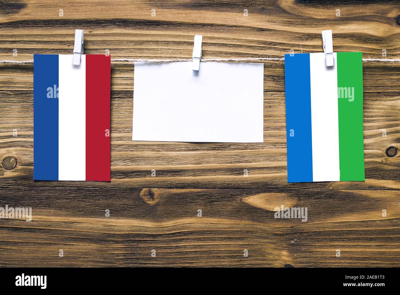 Hanging flags of Netherlands and Sierra Leone attached to rope with clothes pins with copy space on white note paper on wooden background.Diplomatic r Stock Photo