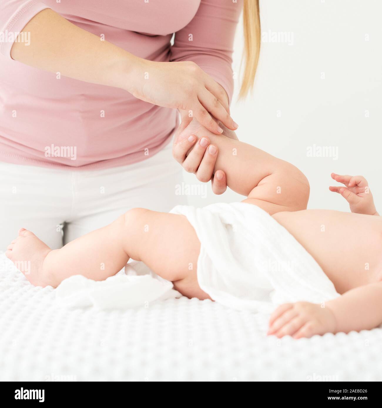 Baby massage. Female therapist gently massaging babys foot. Doctor examining infant baby boy. Stock Photo