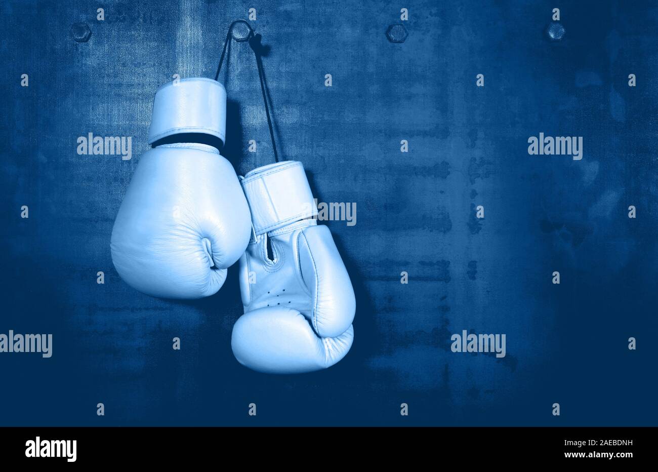 Close up pair of clasic white leather boxing gloves hanging over dark