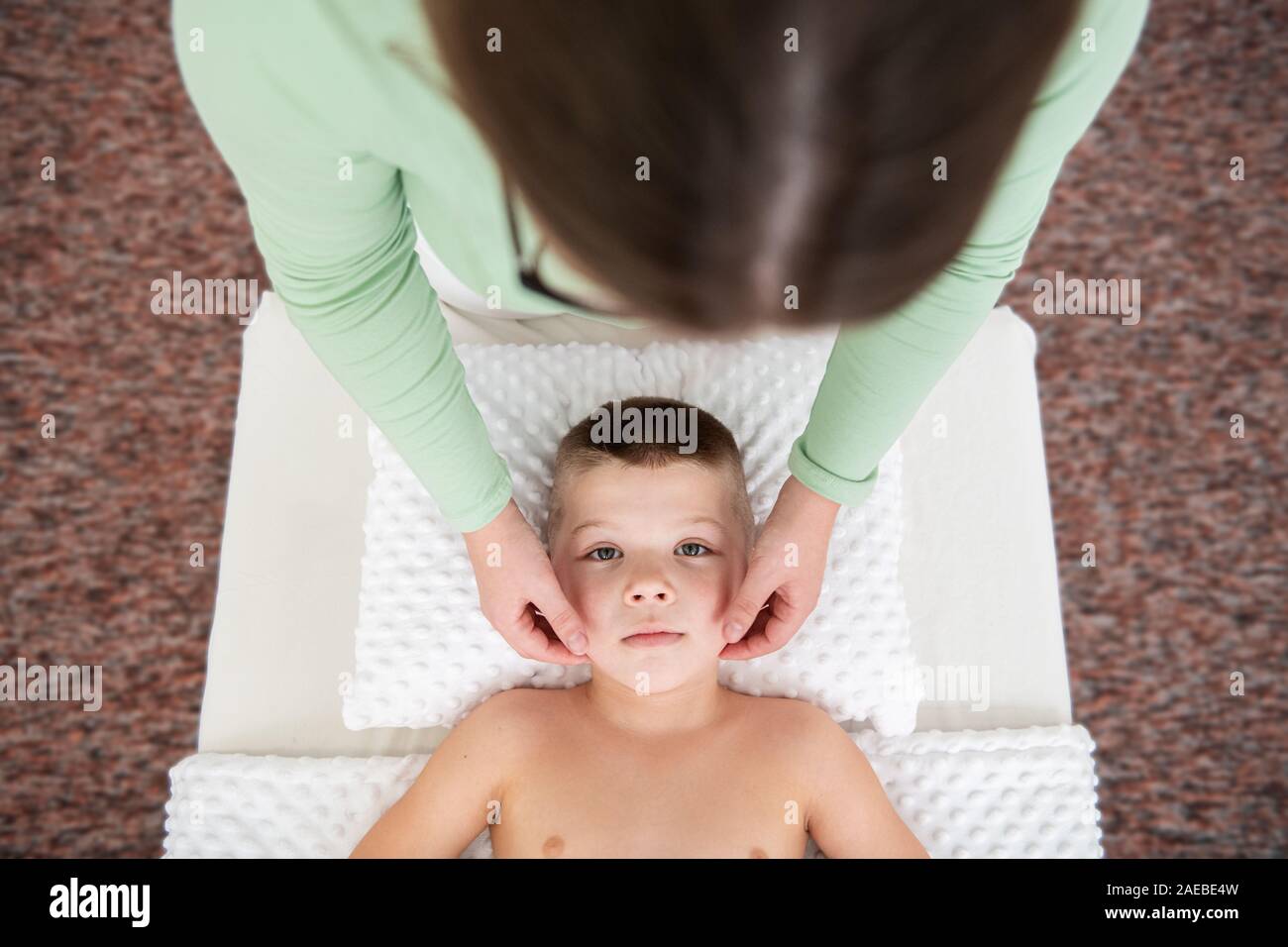 Kids massage concept background. Female therapist giving a young boy