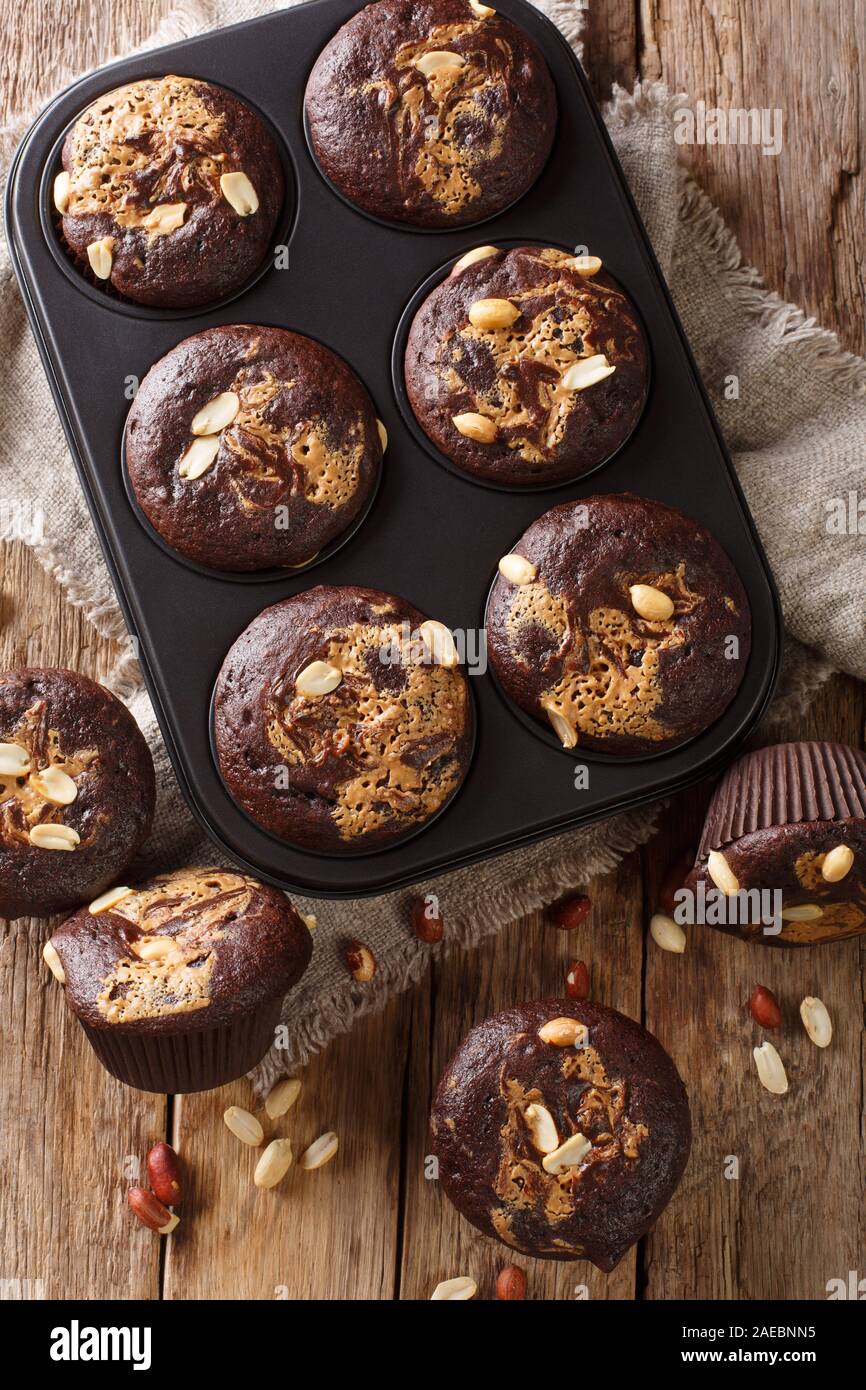 Chocolate peanut muffins in a baking dish on the table. Vertical top view from above Stock Photo