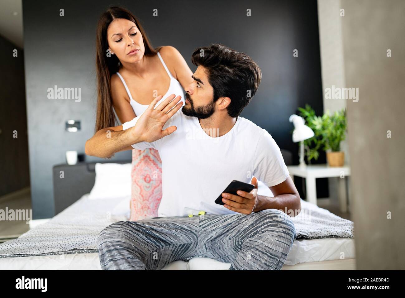 Young shocked wife caught husband on cheating snooping his messages with lover on smartphone Stock Photo